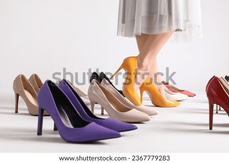 Female legs and many stylish high heels on grey background