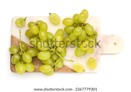 Board with fresh green grapes on white background