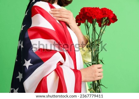 Young woman with USA flag and carnation flowers on green background, closeup. Veterans Day celebration