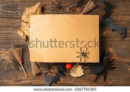 Blank greeting card with Halloween decorations on brown wooden background
