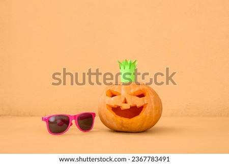 Carved pumpkins for Halloween with crown and stylish sunglasses on orange background