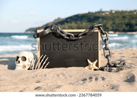 Skull for Halloween with chalkboard, hand, chain and starfish on beach