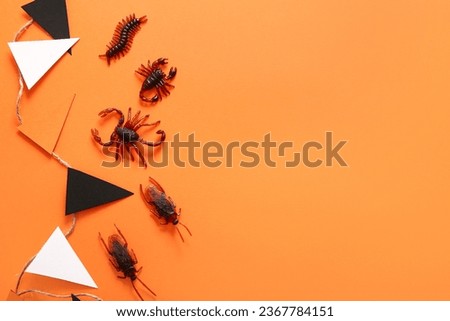 Halloween composition with candy bugs and garland on orange background