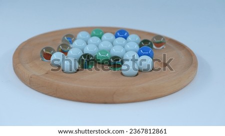 Various colored and patterned marbles on a wooden decor on a white background