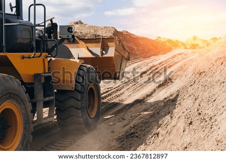 Open pit mine quarry, yellow excavator transporting sand with sunlight. Concept heavy machinery of construction industry. Royalty-Free Stock Photo #2367812897