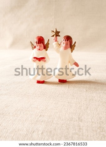 Pair of angels figures, one holding bible, and another holding a star, Christmas decoration