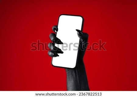 A black hand holds a phone, on a red background. Royalty-Free Stock Photo #2367822513