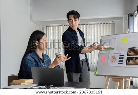 Young businessman explains work plan in meeting to teammates in conference room.