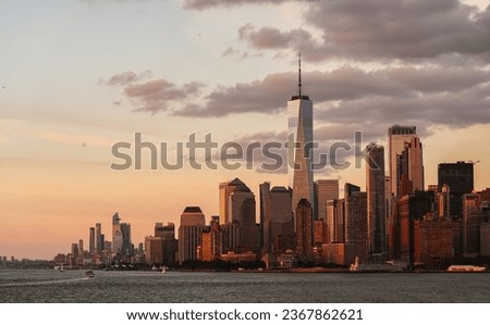 Sunset over Manhattan. Landscape photo from the ferry, view to New York skyline landmarks skyscrapers office buildings under a beautiful sunset sky. Travel to America. Royalty-Free Stock Photo #2367862621