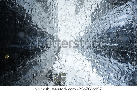 Tall skyscraper office buildings from New York photographed through a wet glass during a powerful summer rain. Abstract image with modern architecture.