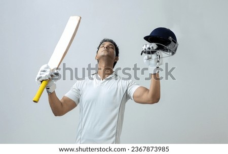 Indian man in cricket dress holding bat and helmet looking towards the sky celebrating century , cricket concept