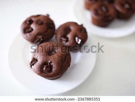 Close-up of delicious chocolate muffins with crispy top served on white plate. Homemade tasty cupcakes with cocoa stuffing. Yummy dessert and sweets concept