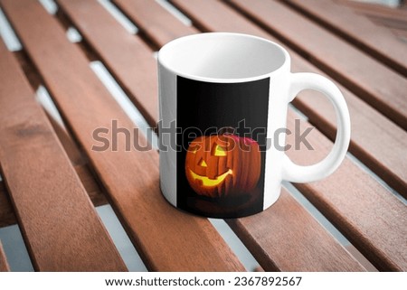 A special cup made for Halloween, lying on a table, mockup pumpkin picture on cup. October and autumn, thanksgiving, Halloween concept.