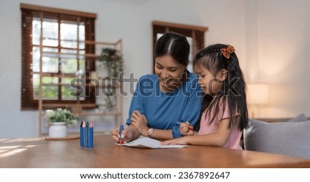 Happy family mother and daughter study or draw together at home in living room
