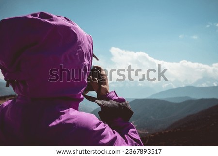 Woman hiker taking photo with camera in winter mountains