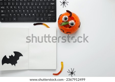 Workplace is decorated for Halloween. Holiday attributes at work. Creepy sweets, pumpkins, skull. Flat lay, copy space, top view