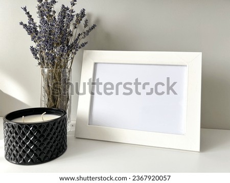 Blank photo frame mockup, white. Bouquet of lavender and scented candle. Scandinavian interior design. Light background. Foreground. Copy space