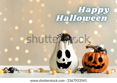 Pumpkins are laying on white floor surface with colorful background. The spiders kept on pumpkins and on floor and some sweets too. Happy Halloween day, 31st October. Autumn, thanksgiving, Halloween.