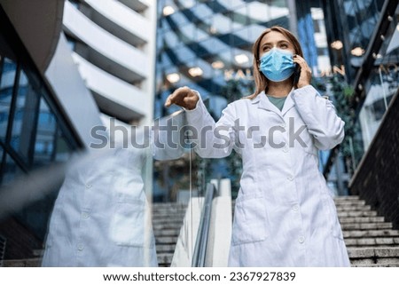 Doctor, phone call and talking for communication, conversation and telehealth with contact outdoor in the city. Medical worker with face mask on or healthcare expert speaking on smartphone on break.
