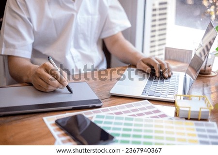 Young graphic designer using graphics tablet to do his work at desk