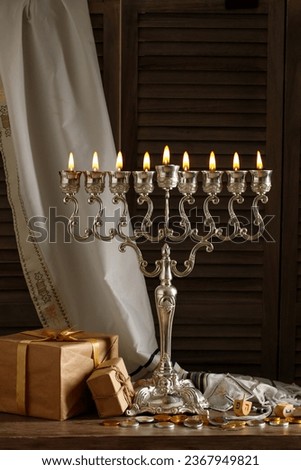 Jewish religious holiday Hanukkah with holiday Hanukkah (traditional candelabra), tallit, gift boxes, wooden dreidels (spinning top), chocolate coins on wood background Royalty-Free Stock Photo #2367949821