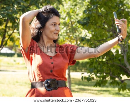 A young girl takes a selfie in the park. A woman holds a smartphone and takes photos on the street.