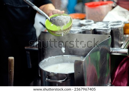 Serving Tradition: Merchant Ladling Chinese Porridge for a Customer