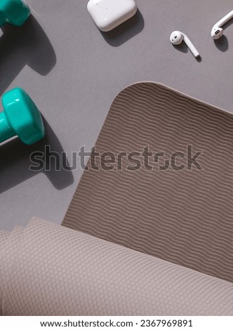 Sport or workout concept flat lay with blue dumbbells, yoga mat and white wireless headphones on the grey background. Copy space Royalty-Free Stock Photo #2367969891