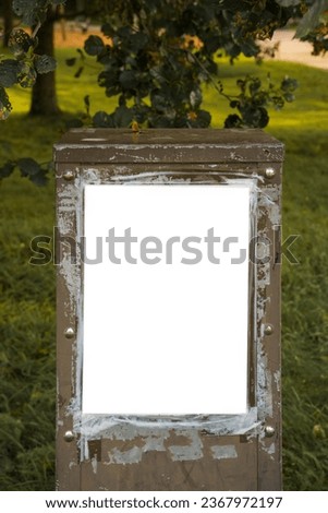White poster template on old brown electric box in a park