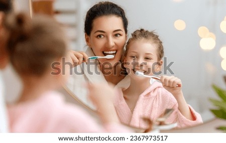 Happy family! Mother and daughter child girl are brushing teeth toothbrushes in the bathroom. Royalty-Free Stock Photo #2367973517
