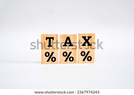 A wooden block with icon percentage symbol and word tax on white surface. Interest rate financial and mortgage rates concept