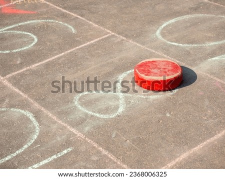 Red hockey puck and chalk on playground, closeup of photo