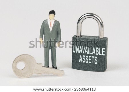 Business concept. On a white surface there is a figurine of a businessman, a key and a lock with the inscription - Unavailable assets