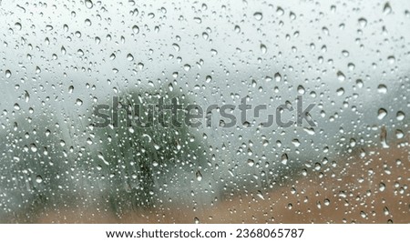 Explore our stunning abstract photograph of rain-kissed glass, revealing hints of a serene landscape. Perfect for stock agencies, this high-quality texture captures the beauty of raindrops.