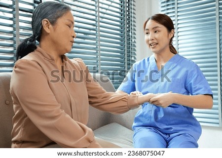 nurse taking care and physical rehabilitation therapy exercise with senior woman on sofa