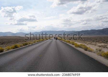 Motorcycle road trip with desert on both sides and horizon surrounded by mountains, Nevada - USA.