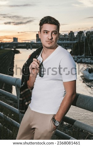 man caucasian model millionaire yachtsman in a white T-shirt with a watch on his wrist, stands on the pier of the yacht club at sunset Royalty-Free Stock Photo #2368081461