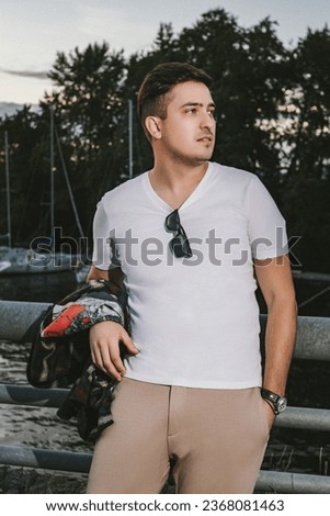 man caucasian model millionaire yachtsman in a white T-shirt with a watch on his wrist, stands on the pier of the yacht club at sunset Royalty-Free Stock Photo #2368081463
