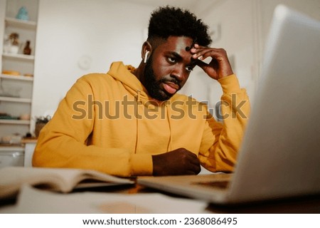 An unfocused casual businessman is having a video call on a laptop with colleagues and looking at it. A man has a boring business video call with colleagues on a laptop from home.