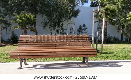 A bench in a public park in Lisbon near a high white wall
