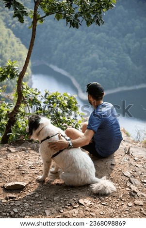 man and dog on mountain top overlooking a lake