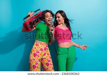 Photo of excited pretty girls dressed colorful outfits singing mic listening boom box music isolated blue color background