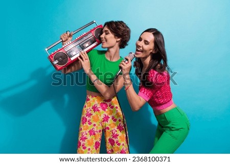 Photo of cheerful positive girls dressed colorful outfits singing karaoke listening boom box music isolated blue color background