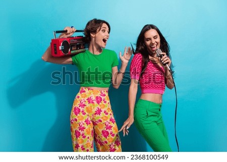 Photo of cute impressed girls dressed colorful outfits singing microphone listening boom box isolated blue color background