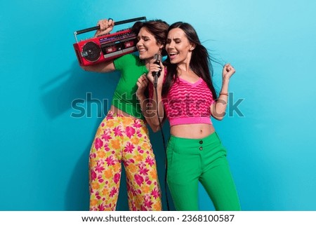Photo of pretty excited girls dressed colorful outfits singing microphone enjoying boom box songs isolated blue color background