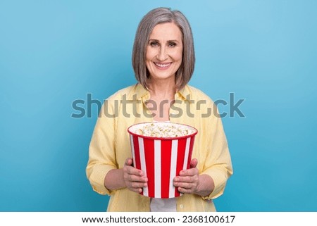 Photo of funky positive person beaming smile arms hold big pop corn bucket isolated on blue color background