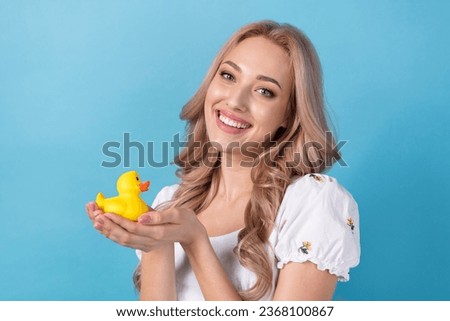 Photo of sweet shiny woman dressed white top smiling holding hands little yellow duck isolated blue color background Royalty-Free Stock Photo #2368100867
