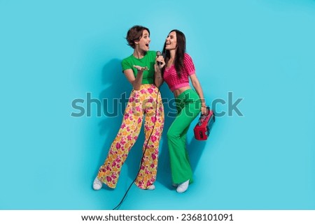 Full body photo of two funny gorgeous girlfriends lesbians together singers vocal music boombox karaoke isolated on blue color background