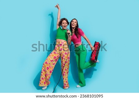 Full body size photo of two girlfriends old school boombox cassette recorder hand up rock roll singer isolated on blue color background