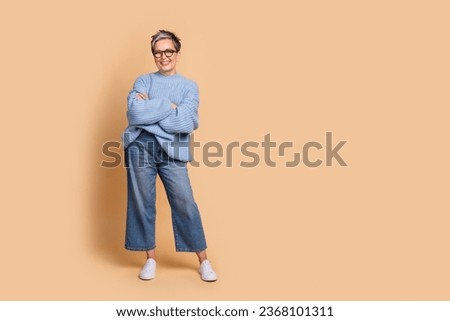 Full size photo of attractive senior woman crossed hands posing dressed stylish blue knitted clothes isolated on beige color background